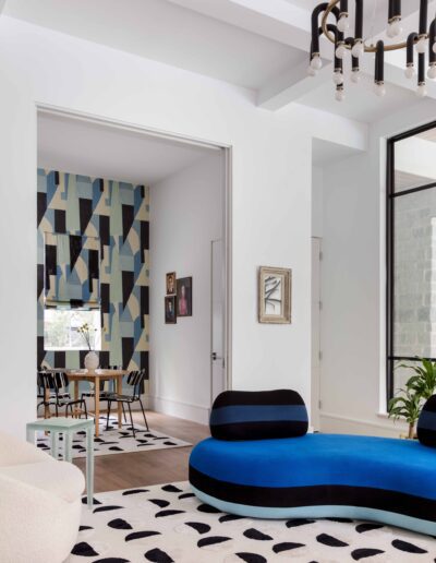 Modern living room with geometric decor, featuring a blue circular sofa, spotty rug, and stylish hanging lights.